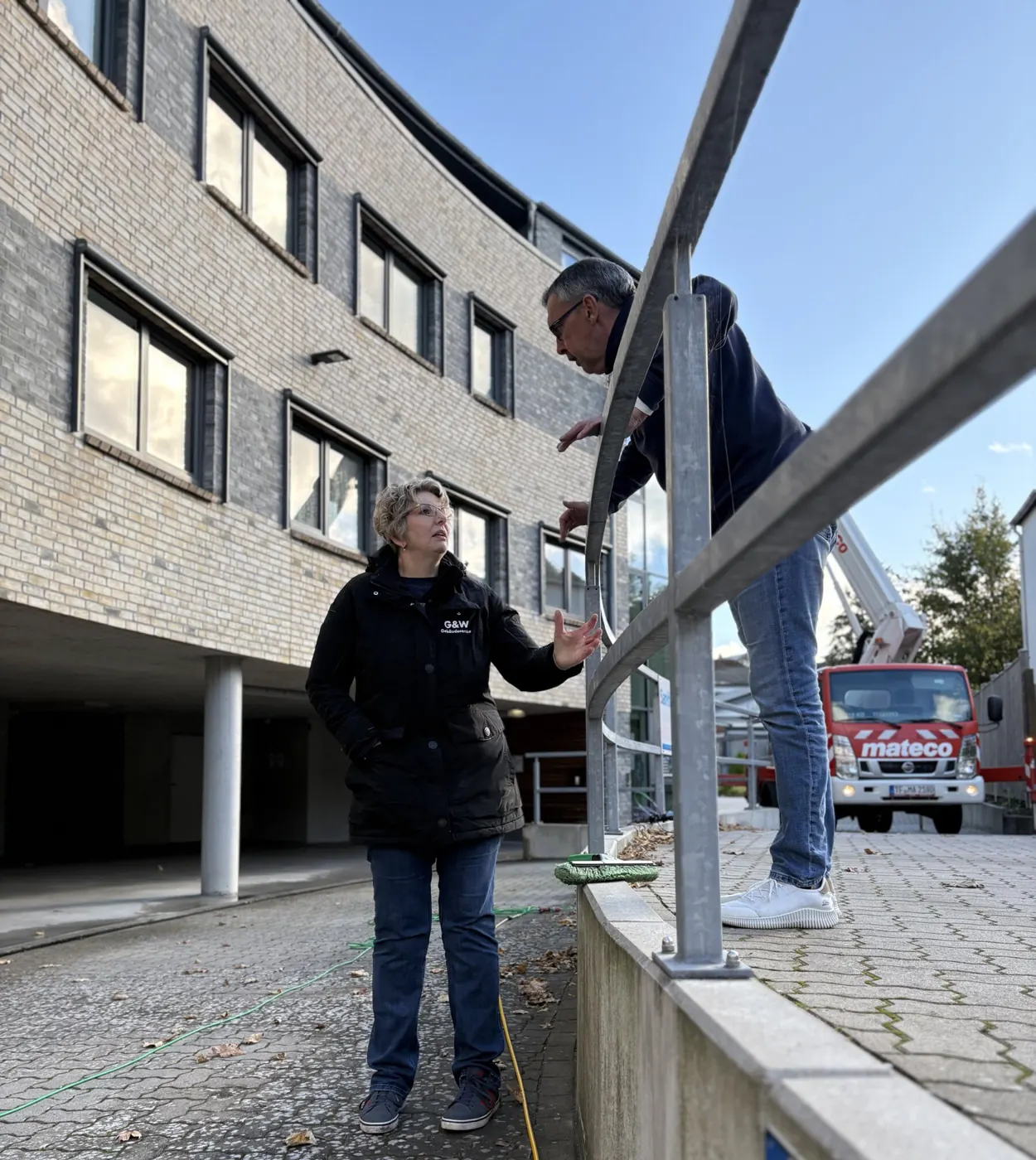 Die Inhaber von G&W vor einem Bürogebäude, im Hintergrund eine Hebebühne.