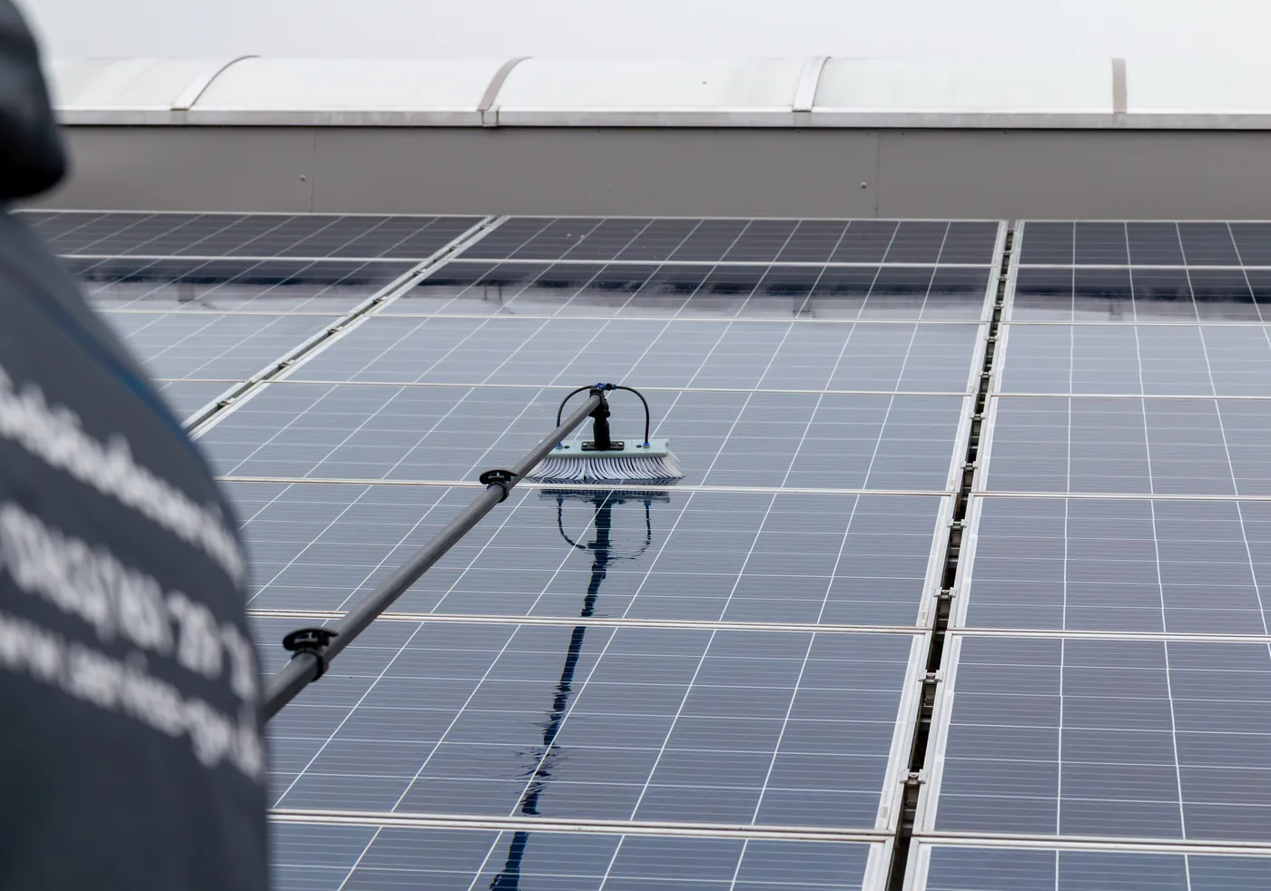 Ein Mitarbeiter von G&W reinigt eine Solaranlage mit der Teleskopbürste.